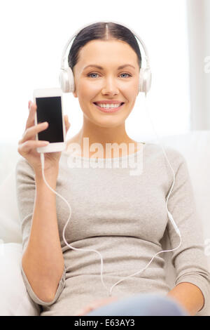 Frau mit Smartphone und Kopfhörer zu Hause Stockfoto