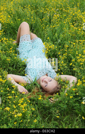 glückliche junge Frau entspannend in einem Feld von Blumen Stockfoto