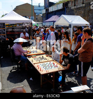 Mann spielt Schach gegen 4 andere, die alle zur gleichen Zeit in der Brick Lane, Shoreditch, London, England Stockfoto