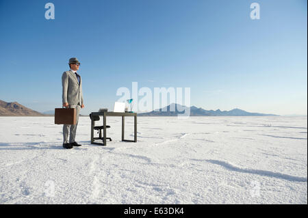 Geschäftsmann, stehen neben mobilen Schreibtisch im Freien auf dramatische Weiße Wüste Landschaft Stockfoto