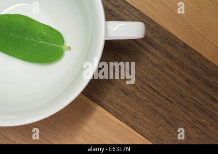 Weißware Cup, Salbeiblatt, Nussbaum, Teak Oberfläche, Verkleidung Stockfoto