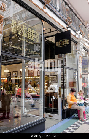 Durch ein Fenster von BarberBarber Herren nur Friseur mit Dame saß draußen im Barton Arcade, Manchester, England, Großbritannien, Großbritannien Stockfoto