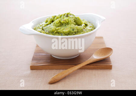 Handgemachte Guacamole in Schüssel mit Löffel servieren. Stockfoto