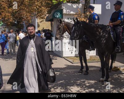 Kiew, Ukraine. 13. August 2014. Der Priester geht vorbei an berittene Polizei außerhalb der Mauern von der Kiewer Höhlenkloster. 13. August 2014. --Der Rat der Bischöfe der ukrainischen orthodoxen Kirche gewählt Primas von der ukrainischen orthodoxen Kirche des Moskauer Patriarchats Locum Tenens Metropolit von Kiew metropolitan Department of Chernovtsy und Bukowina Onufry.Church des Moskauer Patriarchats. Wahlen finden am vierzigsten Tag des Todes von Metropolitan Wladimir statt. Bildnachweis: Igor Golovniov/ZUMA Draht/Alamy Live-Nachrichten Stockfoto