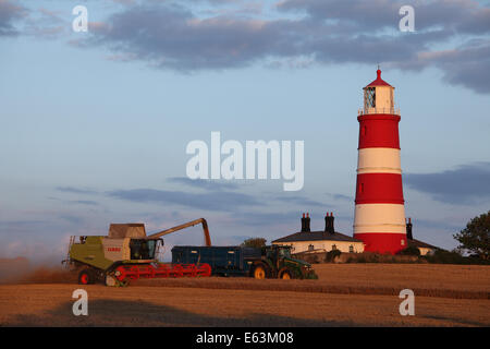 Happisburgh, Norfolk, Großbritannien. 13. August 2014. Bauern-Rennen zu bringen in die Ernte des Weizens, nach heftigen vor kurzem Regenfällen getroffen die Grafschaft & stark verzögerte Ernte. Hier ist ein Claas Lexion 760 TT vor Happisburgh Leuchtturm bei Sonnenuntergang ernten. Bildnachweis: Paul Lilley/Digitalshot/Alamy Live-Nachrichten Stockfoto