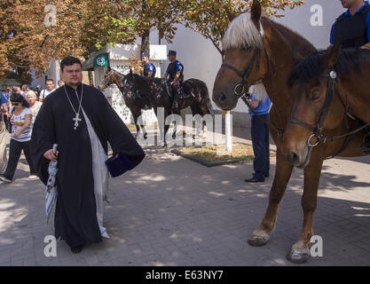 Ukraine. 13. August 2014. Der Priester geht vorbei an berittene Polizei außerhalb der Mauern von der Kiewer Höhlenkloster. 13. August 2014. --Der Rat der Bischöfe der ukrainischen orthodoxen Kirche gewählt Primas von der ukrainischen orthodoxen Kirche des Moskauer Patriarchats Locum Tenens Metropolit von Kiew metropolitan Department of Chernovtsy und Bukowina Onufry.Church des Moskauer Patriarchats. Wahlen finden am vierzigsten Tag des Todes von Metropolitan Wladimir statt. Bildnachweis: Igor Golovniov/ZUMA Draht/Alamy Live-Nachrichten Stockfoto