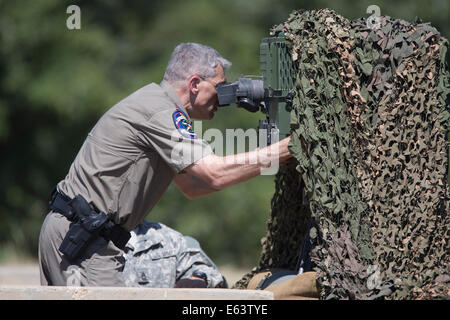 Bastrop, TX, USA. 13. August 2014. Texas Department of Public Safety Director Steve McCraw schaut durch ein Raytheon High-Tech-optisches Gerät als er und Gouverneur Rick Perry Ansicht Texas National Guard Operations bei Camp Swift östlich von Austin wie Truppen für ein Ende des Monats Bereitstellung an der texanischen Grenze mit Mexiko vorzubereiten. Bildnachweis: Bob Dämmrich/Alamy Live-Nachrichten Stockfoto