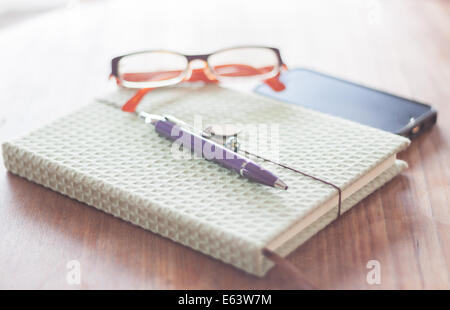 Notizbuch und Stift mit Brille auf Holztisch, Fotoarchiv Stockfoto