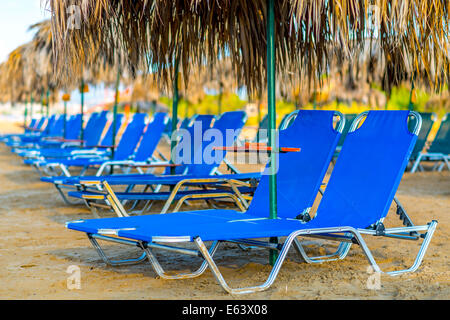 Sandstrand mit Liegestühlen und mit Stroh Sonnenschirmen in Kreta, Griechenland Stockfoto