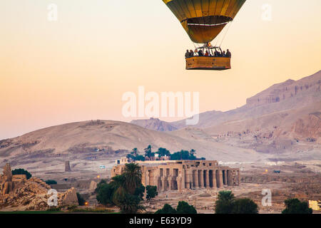 Heißluftballon überfliegen das Ramesseum am Westufer des Nils in Ägypten bei Sonnenaufgang. Stockfoto