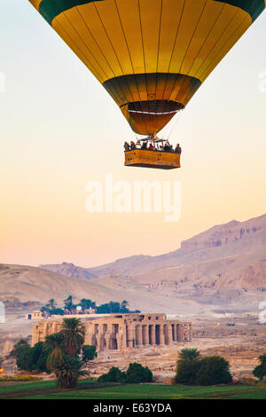 Heißluftballon überfliegen das Ramesseum am Westufer des Nils in Ägypten bei Sonnenaufgang. Stockfoto