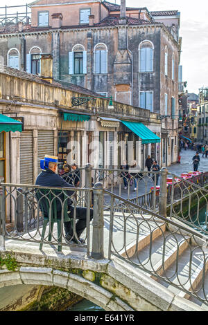 Gondoliere sitzen auf Brücke über einen Kanal in Venedig Stockfoto