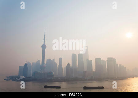Sonnenaufgang über der Skyline von Pudong & Lastkähne am Huangpu-Fluss, Shanghai, China Stockfoto