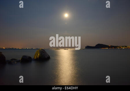 Mondlicht spiegelt sich auf dem ruhigen Dienst des Gardasees in der Nacht Stockfoto