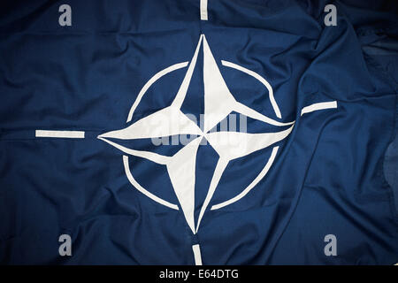 Die Flagge der North Atlantic Treaty Organization (NATO) besteht aus einem dunkel blauen Feld aufgeladen mit einem weißen Windrose-Emblem, mit vier weißen Linien, die von den vier Himmelsrichtungen ausstrahlt. Stockfoto