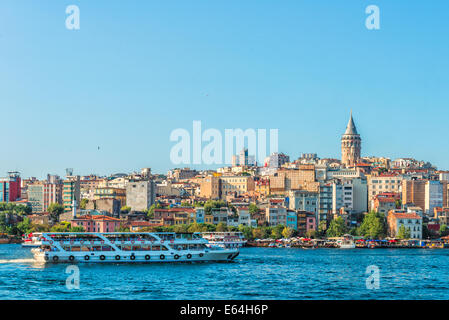 Eine Fähre verläuft entlang des Bosporus mit Galata-Turm in der Ferne. Stockfoto