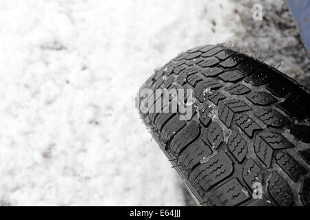 Nahaufnahme von Winterreifen auf einer verschneiten Straße Stockfoto