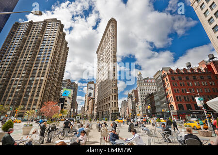 Leute sitzen an den Tischen auf einem kleinen Platz vor dem Flatiron Gebäude. Flatiron District, Midtown Manhattan, New York City, USA. Stockfoto