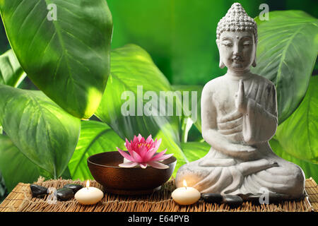 Buddha in Meditation mit Lotusblüte und brennenden Kerzen Stockfoto