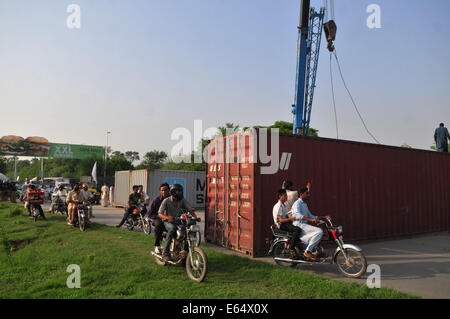 Islamabad, Pakistan. 14. August 2014. Anhänger der pakistanischen Cricketspieler-gedreht-Politiker Imran Khan pass durch eine Straße von einem Container auf einer Autobahn in Islamabad, der Hauptstadt von Pakistan, 14. August 2014 gesperrt. Ein pakistanischer Minister sagte am Donnerstag, dass regierungsfeindliche Demonstranten erlaubt werden, geben die Hauptstadt Islamabad und inszenieren ein Sit-in Credit: Ahmad Kamal/Xinhua/Alamy Live News Stockfoto