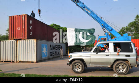 Islamabad, Pakistan. 14. August 2014. Anhänger der pakistanischen Cricketspieler-gedreht-Politiker Imran Khan pass durch eine Straße von einem Container auf einer Autobahn in Islamabad, der Hauptstadt von Pakistan, 14. August 2014 gesperrt. Ein pakistanischer Minister sagte am Donnerstag, dass regierungsfeindliche Demonstranten erlaubt werden, geben die Hauptstadt Islamabad und inszenieren ein Sit-in Credit: Ahmad Kamal/Xinhua/Alamy Live News Stockfoto