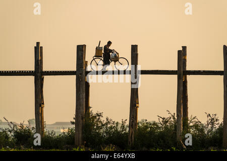 Mann mit dem Fahrrad, zu Fuß auf einem Teakholz Brücke, U Bein Brücke über Thaungthaman See im Abendlicht, Amarapura Stockfoto