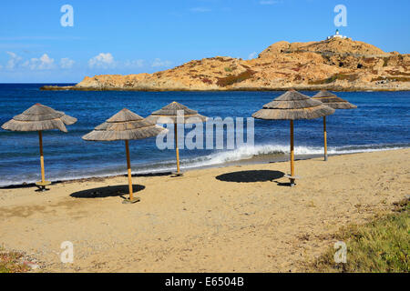 Strohgedeckte Sonnenschirme am Strand, Insel, Île De La Pietra auf der Rückseite, L'Île Rousse, Balagne, Korsika, Frankreich Stockfoto