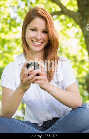 Hübsche Rothaarige SMS im park Stockfoto