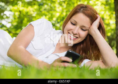 Hübsche Rothaarige liegen auf dem Rasen eine SMS Stockfoto