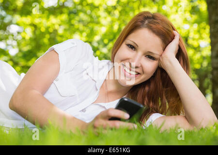 Hübsche Rothaarige liegen auf dem Rasen eine SMS Stockfoto