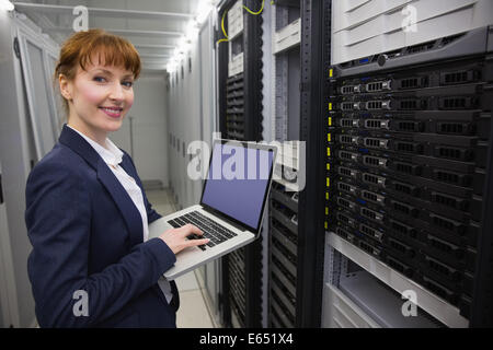 Hübsche Techniker mit Laptop während der Arbeit am Server Stockfoto