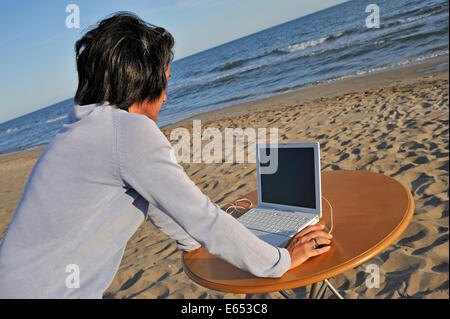 Mid-Adult-Frau mit einem Laptop am Strand - Urlaub Konzept arbeiten Stockfoto