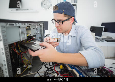 Lächelnde Informatiker arbeiten an defekten Konsole mit Schraubendreher Stockfoto