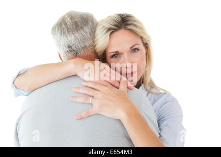Unglücklich Blondine umarmt ihr Ehemann Stockfoto