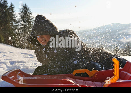 Teenager, die fallen von seinem Schlitten im Schnee in einer Winterlandschaft Stockfoto