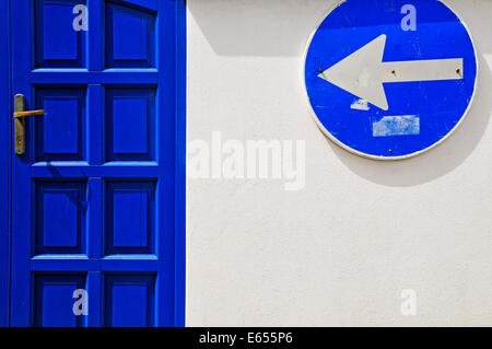 Straße Pfeil Schild und blau Tür auf weißen Wand Stockfoto
