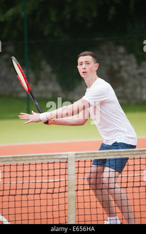 Junge Spieler schlagen Tennisball Stockfoto