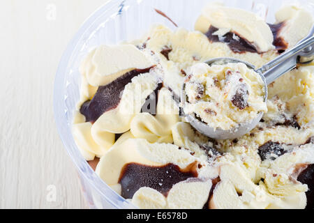 Vanille mit Schoko-Eis Kugel schöpfte aus einem Container auf weißem Holz Hintergrund Stockfoto