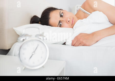 Schöne junge Frau betrachten Wecker Stockfoto