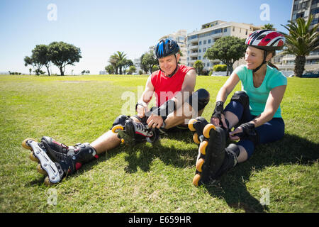 Älteres paar binden ihre Rollerblades auf dem Rasen zu passen Stockfoto