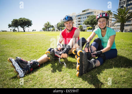 Älteres paar binden ihre Rollerblades auf dem Rasen zu passen Stockfoto