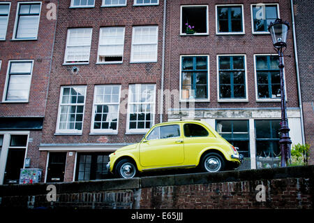 Gelb/grün Fiat 500 parkte auf einem Kanalufer in Amsterdam, Niederlande Stockfoto