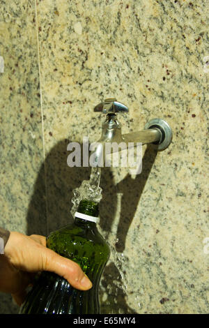 Hand hält eine Flasche mit Wasser aus dem Wasserhahn füllen Stockfoto