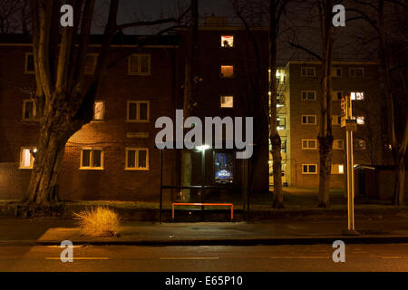 Ein verlassene Weihnachtsbaum wird in einer London Bürgersteig neben einem Block von Wohnungen und Bushaltestelle während der Nachtzeit verworfen. Stockfoto