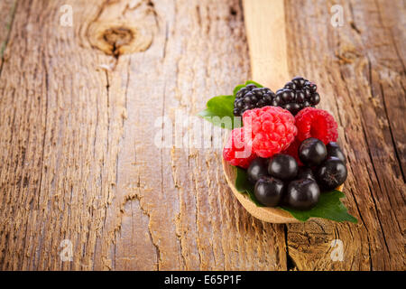 frische Beeren in Holzlöffel auf Holztisch Stockfoto