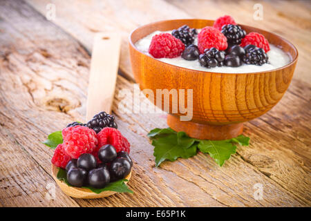 Joghurt mit Waldbeeren in Holzschale auf hölzernen Hintergrund Stockfoto