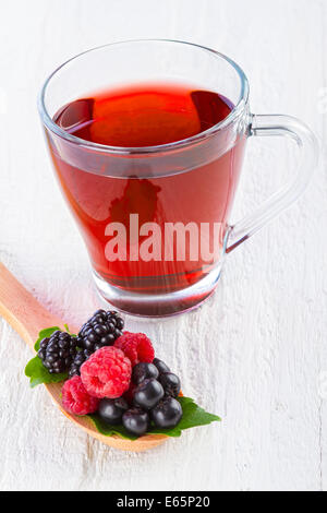 Rote Früchtetee mit Waldbeeren in Holzlöffel auf weißer Holztisch Stockfoto