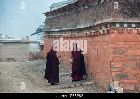 Zwei Mönche in roten Roben sprechen miteinander in Labrang Kloster, Tibet Stockfoto