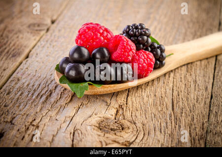 frische Beeren in Holzlöffel auf Holztisch Stockfoto