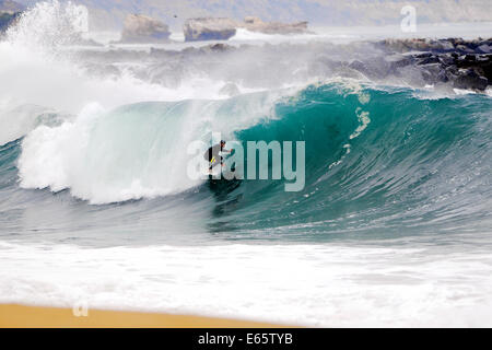 Eine lokale Surfer zieht in eine schwere, Ufer brechen Barrel im seichten Wasser an der Surf Break The Wedge in Newport Beach, Kalifornien Stockfoto